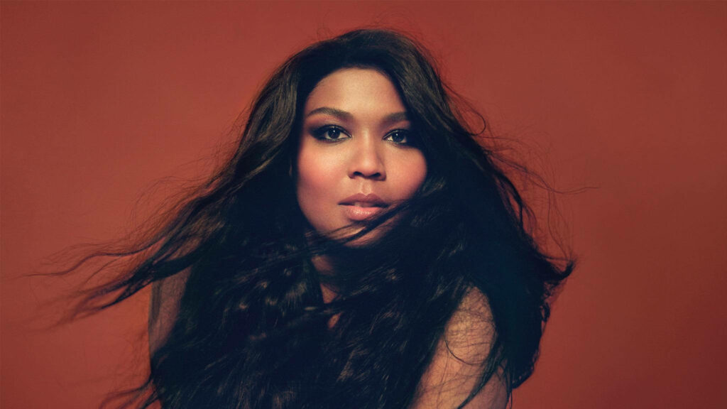 Bold Lizzo Wallpaper: Striking Red-Brown Background & Flowing Hair