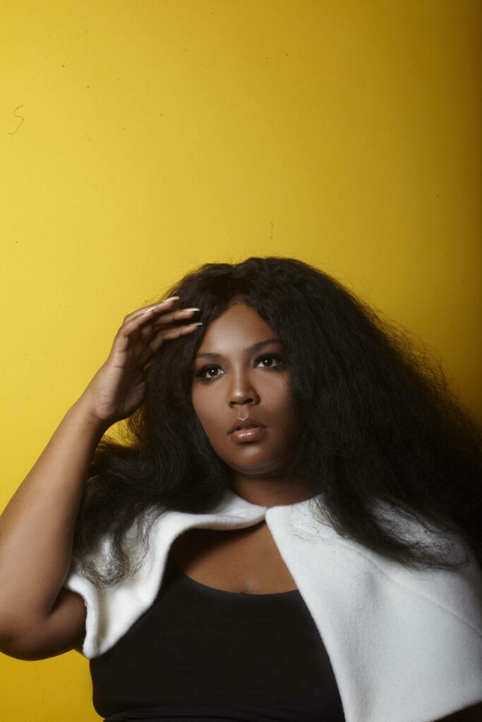 Vibrant Lizzo Wallpaper: Confident Singer in Yellow Background