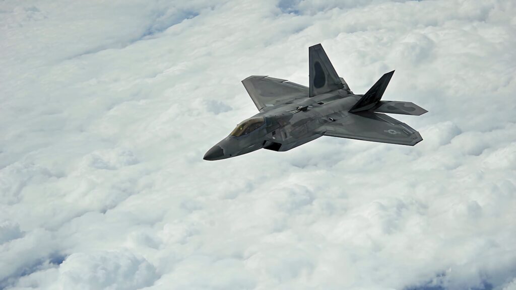 Lockheed Martin F-22 Raptor jet soaring above clouds with sleek stealth design in aviation wallpaper