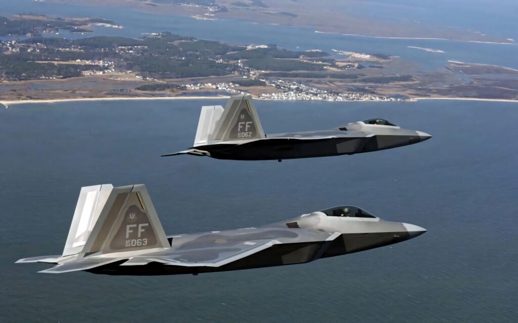 Two Lockheed Martin F-22 Raptor jets fly above coast showcasing stealth design and advanced tech Wallpaper