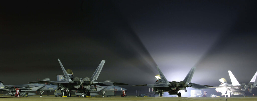 Lockheed Martin F-22 Raptor jets on airfield at night showcasing stealth design and technology Wallpaper