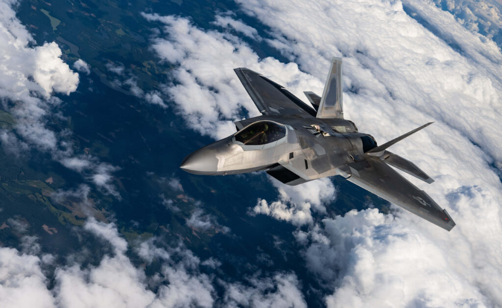Lockheed Martin F-22 Raptor jet soaring above clouds showcasing stealth design and power Wallpaper