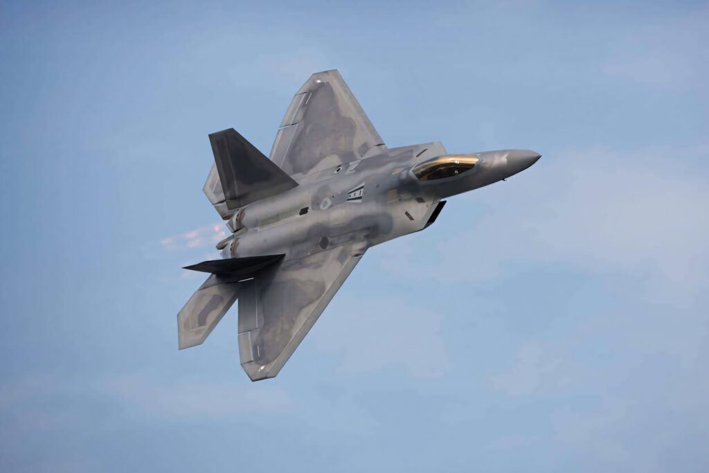 Lockheed Martin F-22 Raptor soaring in blue sky with afterburners and gray stealth design Wallpaper