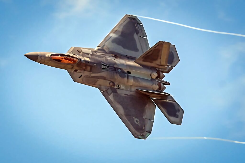 Lockheed Martin F-22 Raptor jet flying in clear sky showcasing sleek stealth design and advanced aerodynamics Wallpaper