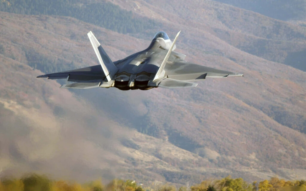 Lockheed Martin F-22 Raptor jets above autumn mountains showcasing advanced stealth design Wallpaper