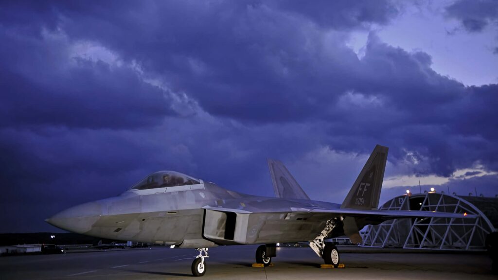 Lockheed Martin F-22 Raptor stealth fighter jet on runway under deep blue evening clouds wallpaper