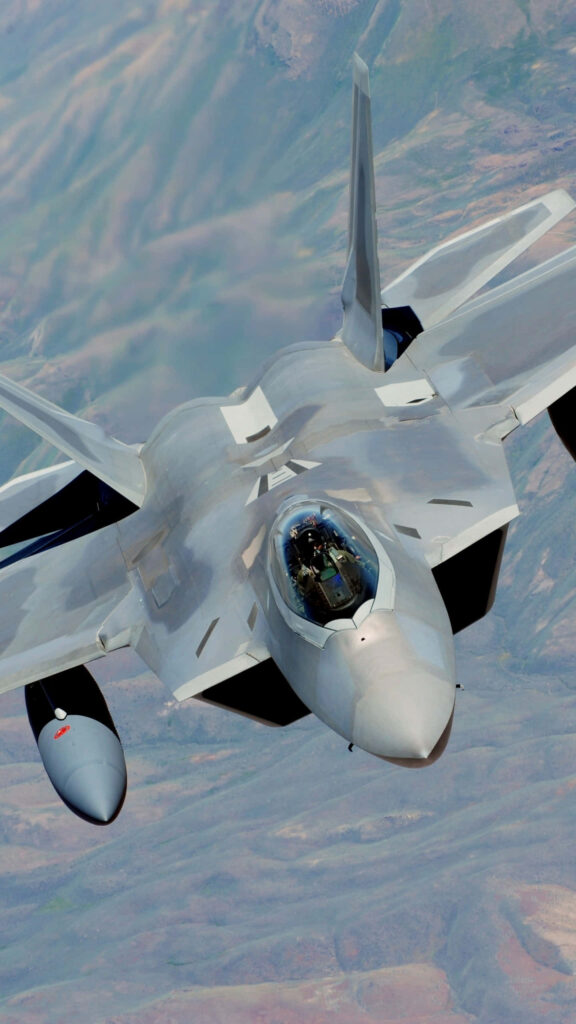 Lockheed Martin F-22 Raptor soaring over rugged terrain showcasing sleek stealth fighter jet design Wallpaper