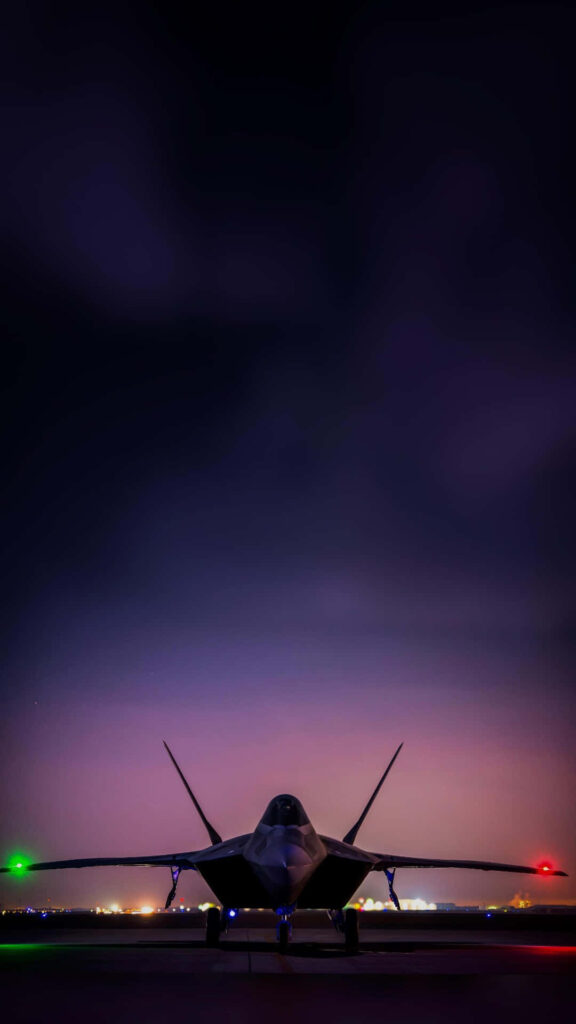 Lockheed Martin F-22 Raptor stealth fighter jet on runway at dusk with violet sky background Wallpaper
