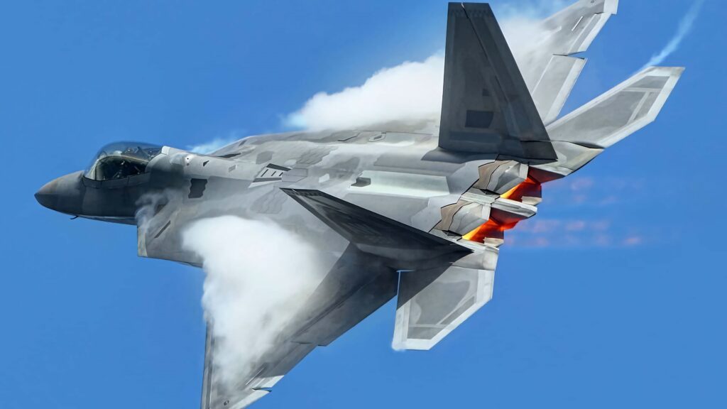 Lockheed Martin F-22 Raptor in flight with afterburners and vapor trails against blue sky wallpaper