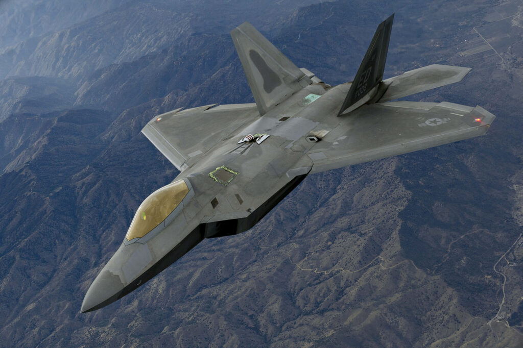 Lockheed Martin F-22 Raptor flying over mountains showcasing stealth design and advanced aerodynamics Wallpaper