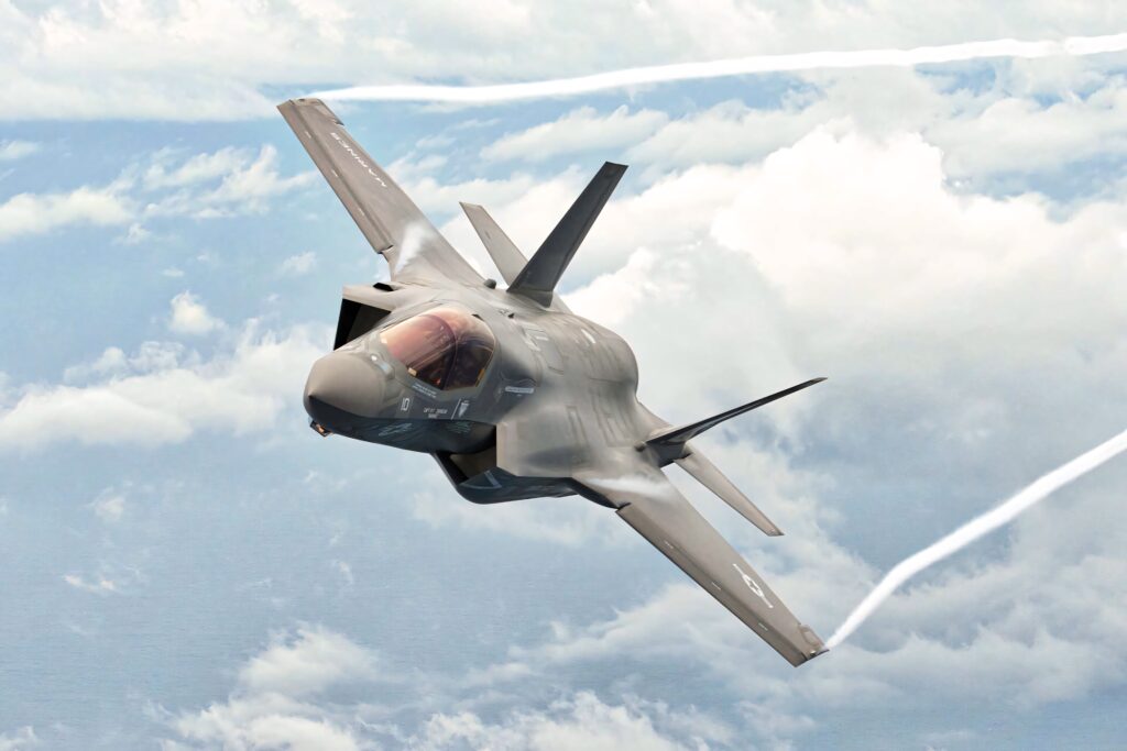 Lockheed Martin F-35 stealth fighter jet soaring above clouds in matte gray advanced aviation design Wallpaper