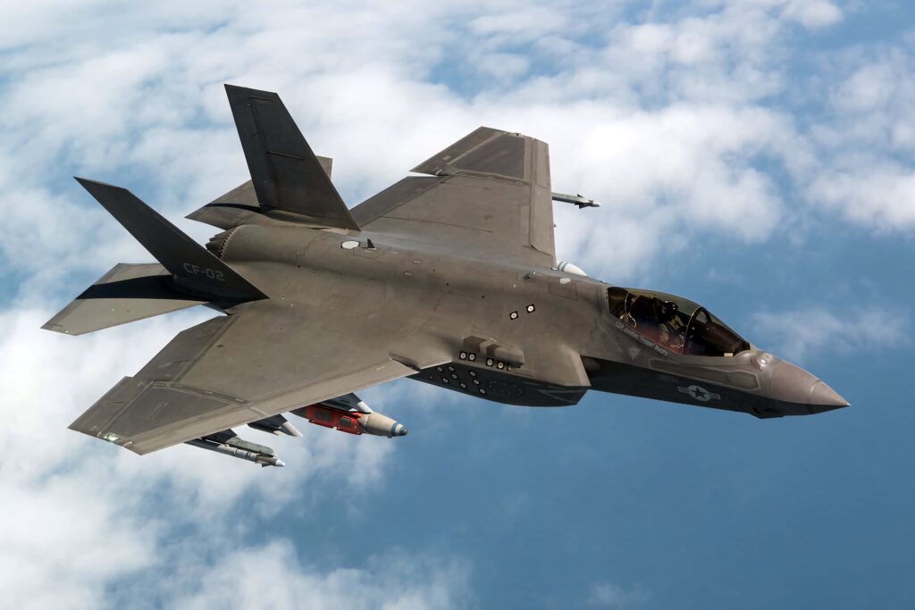 Lockheed Martin F-35 stealth fighter jet soaring above clouds with sleek dark gray design Wallpaper