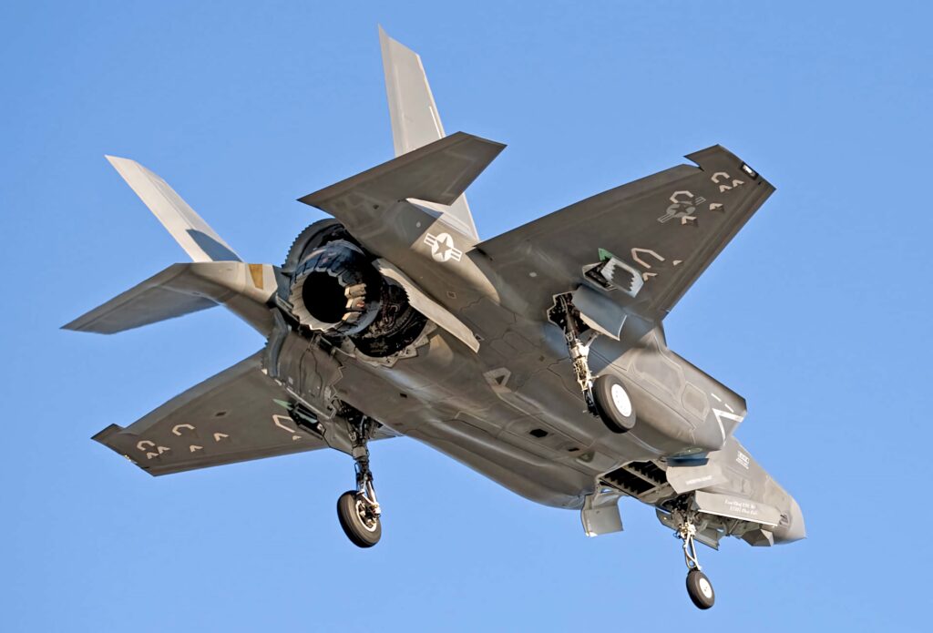 Lockheed Martin F-35 stealth fighter jet in flight against clear blue sky modern military tech wallpaper