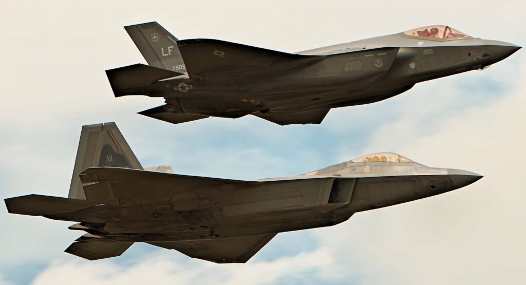 Two advanced fighter jets including sleek Lockheed Martin F-35 flying in soft blue sky wallpaper