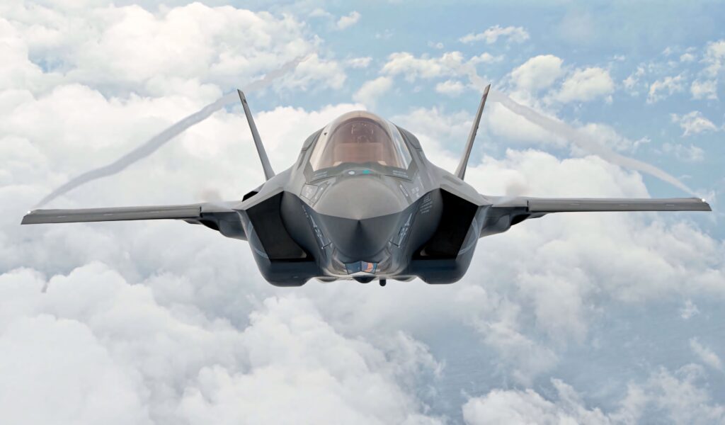 Lockheed Martin F-35 fighter jet soaring above clouds showing sleek stealth design and aerodynamics Wallpaper