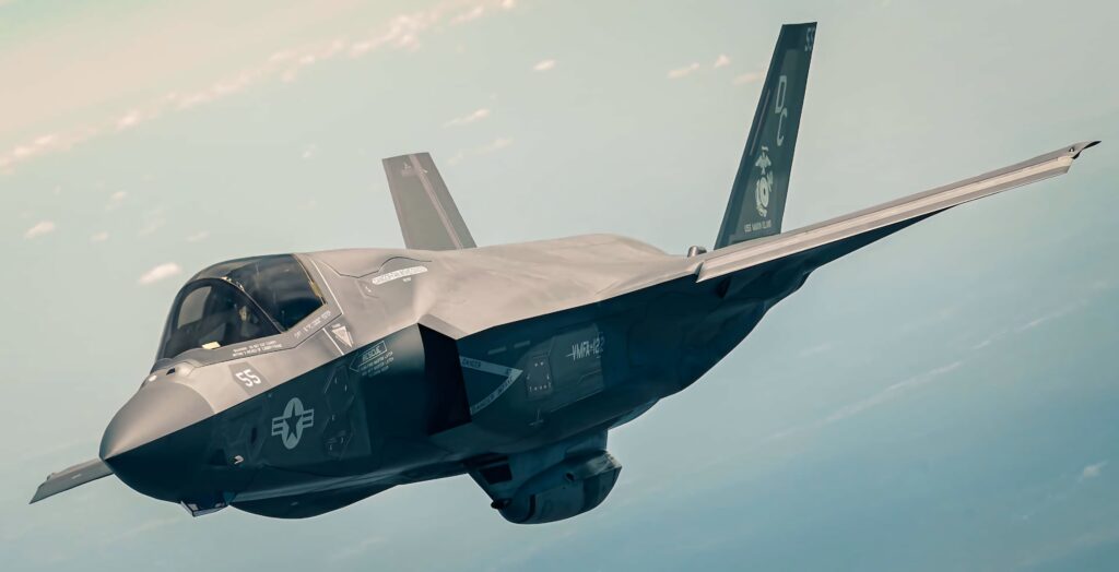 Lockheed Martin F-35 stealth fighter jet in flight with matte gray finish and blurred sky background Wallpaper
