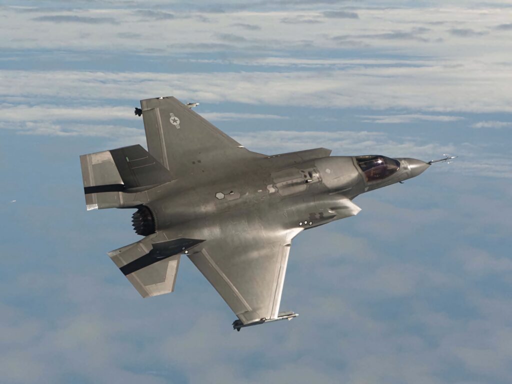 Lockheed Martin F-35 stealth fighter jet soaring above clouds with sleek design and blue sky background Wallpaper