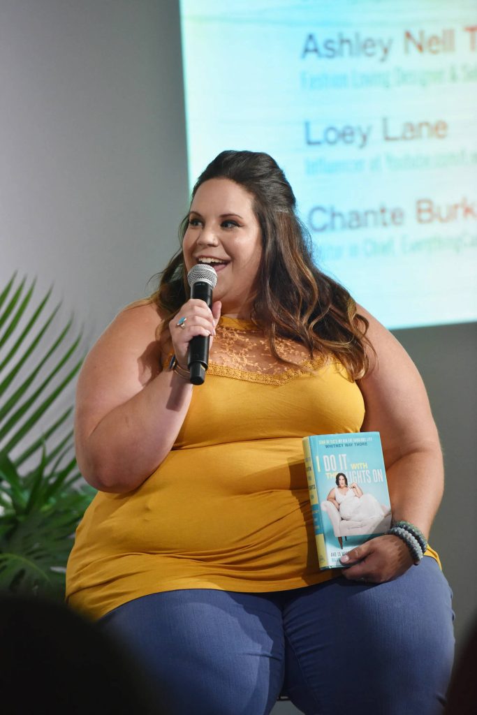 Loey Lane speaking at panel holding microphone and book I Do It With The Lights On vibrant yellow top Wallpaper