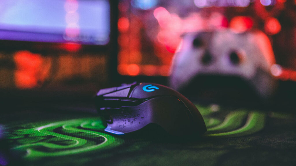 Logitech gaming mouse with vibrant RGB lighting on dynamic blurred gaming setup background Wallpaper