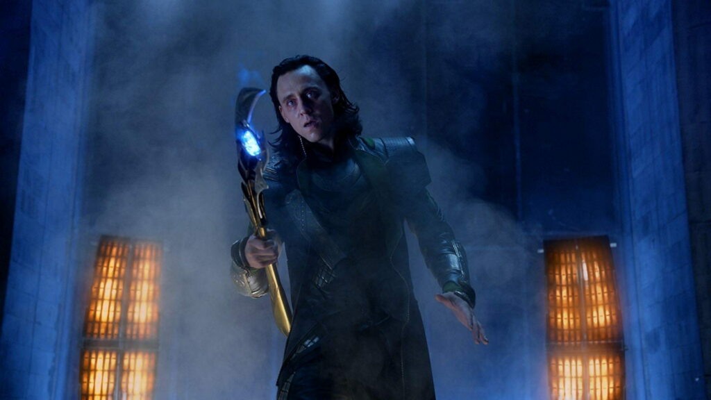 Tom Hiddleston as Loki with glowing blue scepter in smoky cinematic Marvel wallpaper background
