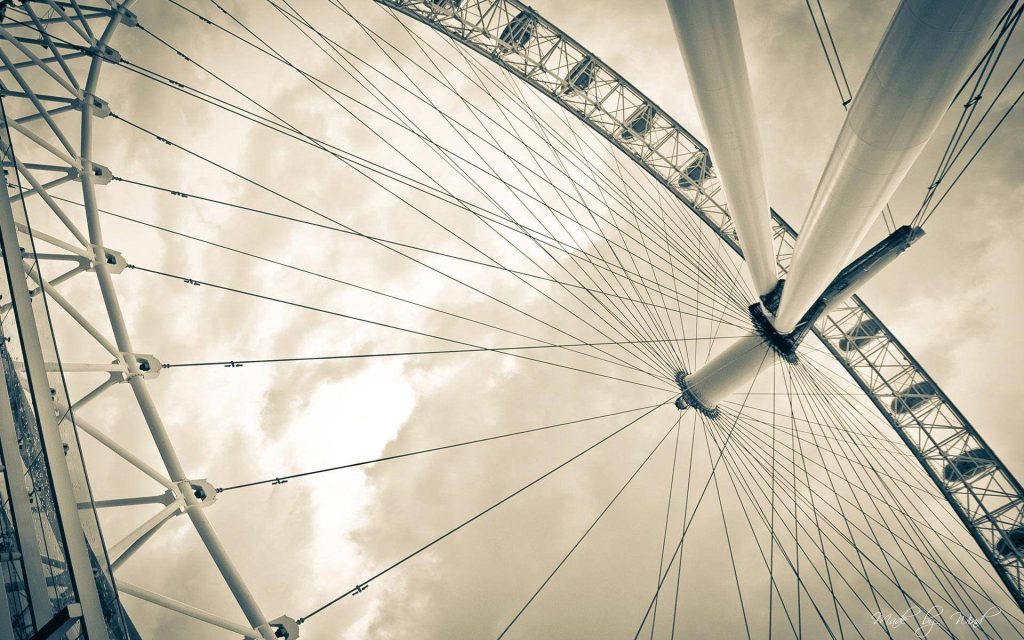 Low-angle sepia London Eye Ferris wheel showing steel cables and central hub against clouds Wallpaper
