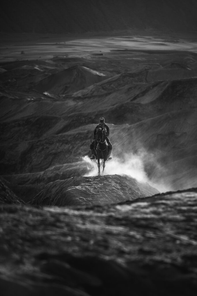 Striking Black and White Wallpaper: Horseman in Rugged Landscape