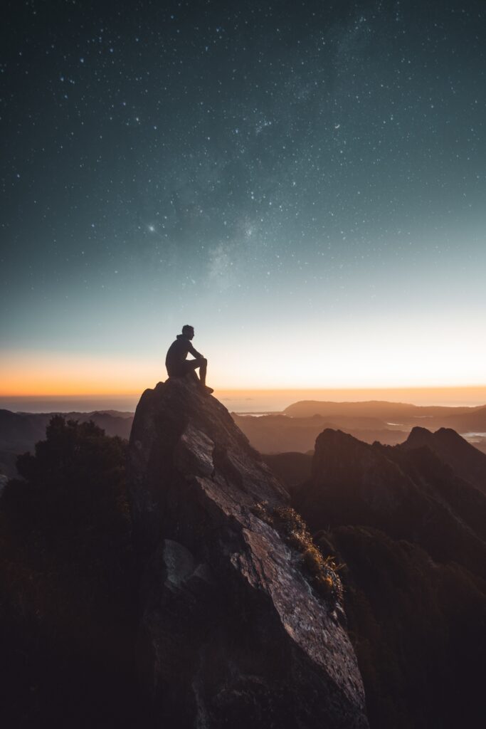 Silhouette on rocky cliff gazing at vibrant Milky Way starry sky twilight night wallpaper background