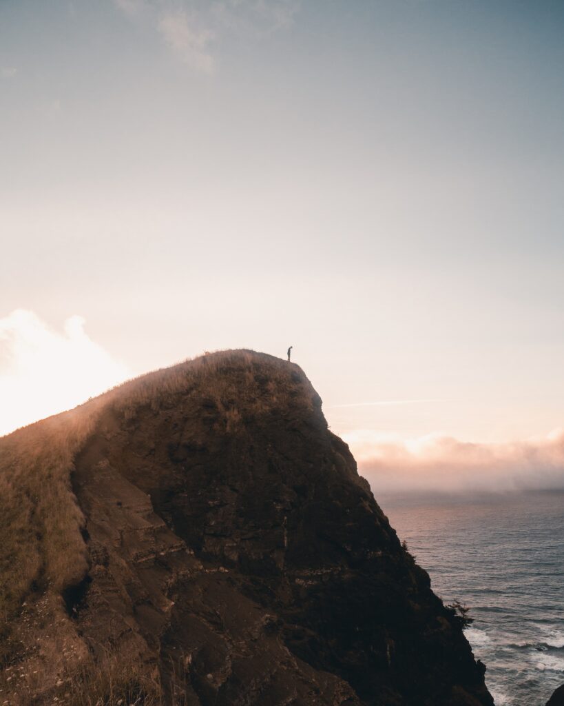 Silhouette on steep cliff at sunrise overlooking ocean dramatic landscape wallpaper background