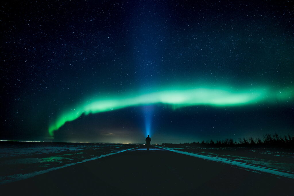 Majestic Aurora Highway: A Captivating 4K Wallpaper of a Solitary Traveller Embracing the Vast Sky