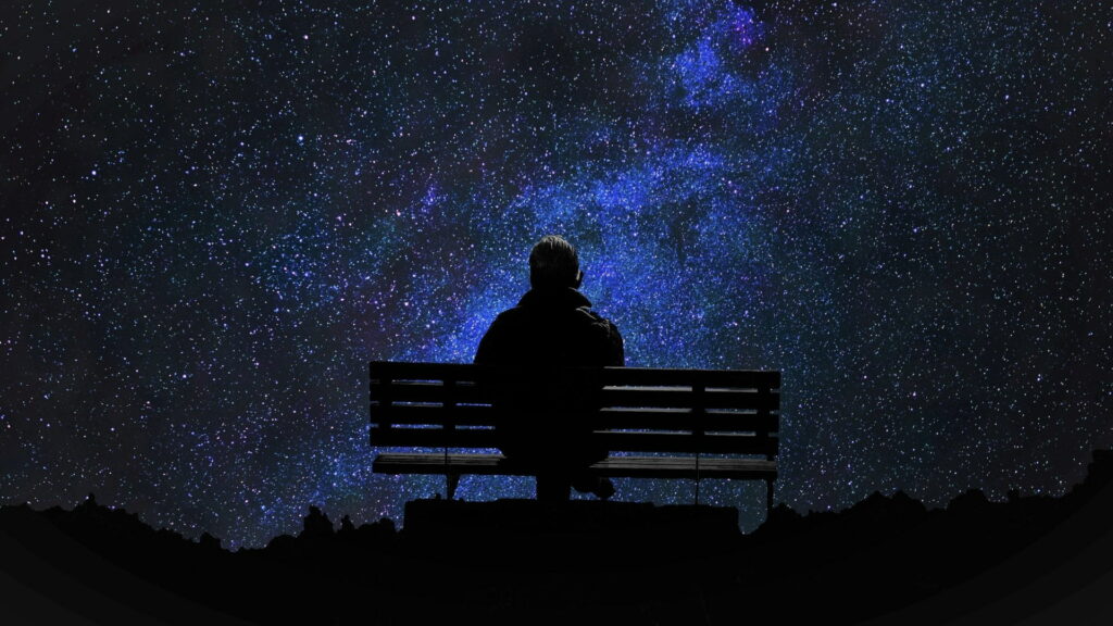 Solitude Under the Starry Sky: Capturing the Loneliness of Men on Bench at Night Wallpaper