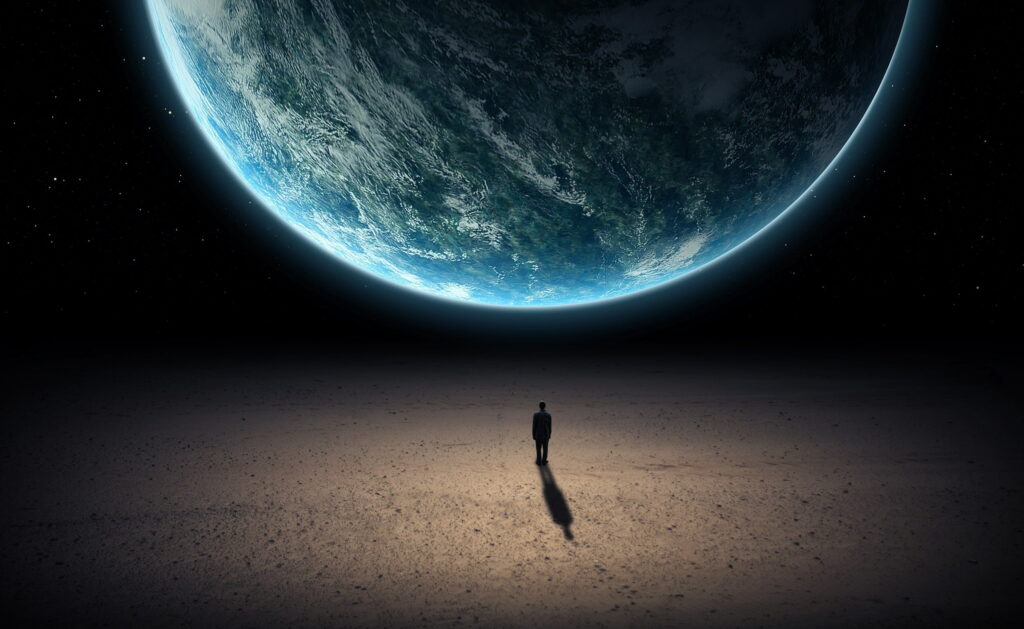 Lone figure in suit on rocky terrain beneath glowing Earth and starry cosmic sky wallpaper background