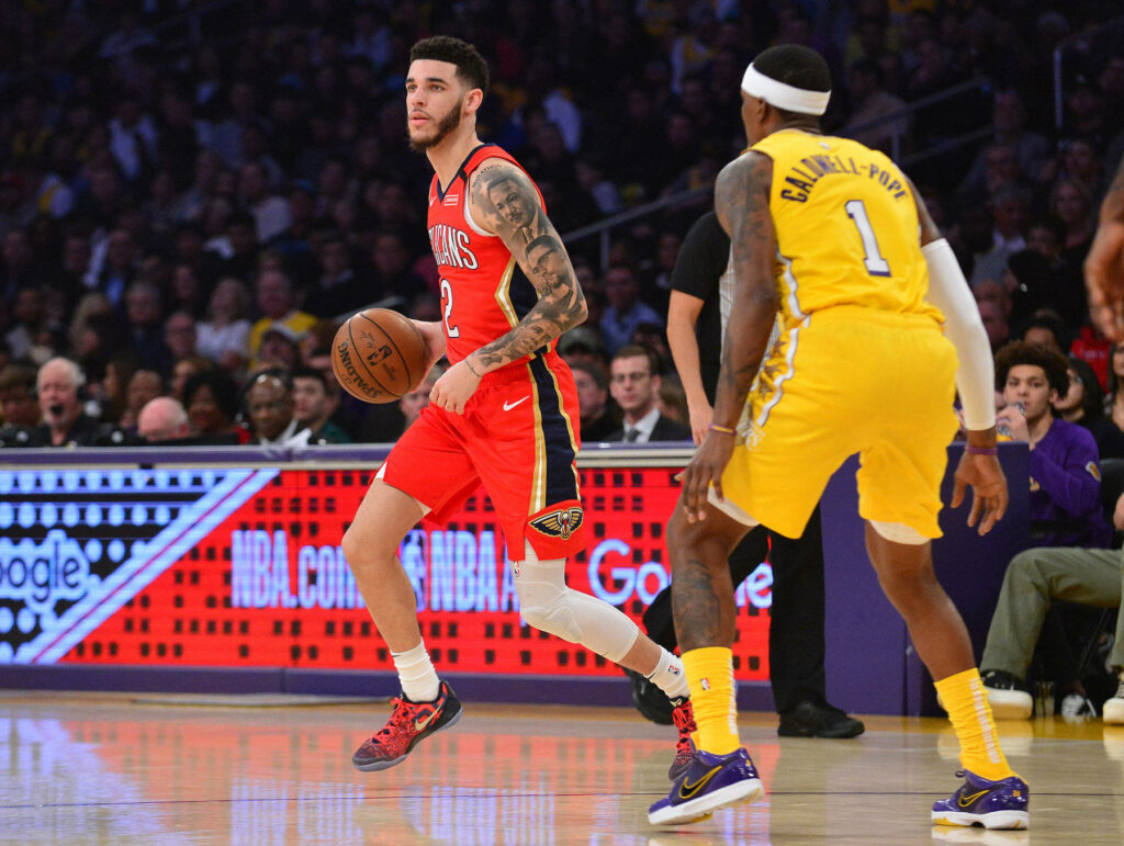 Lonzo Ball dribbling basketball on vibrant NBA court with red yellow uniforms and packed crowd Wallpaper