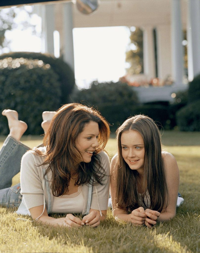 Lorelai and Rory Gilmore laughing on a sunlit lawn cozy cheerful Gilmore Girls wallpaper background