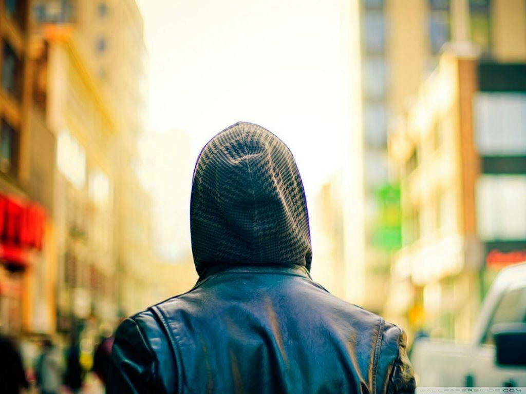 Solitary boy walks the street wearing a hoodie Wallpaper