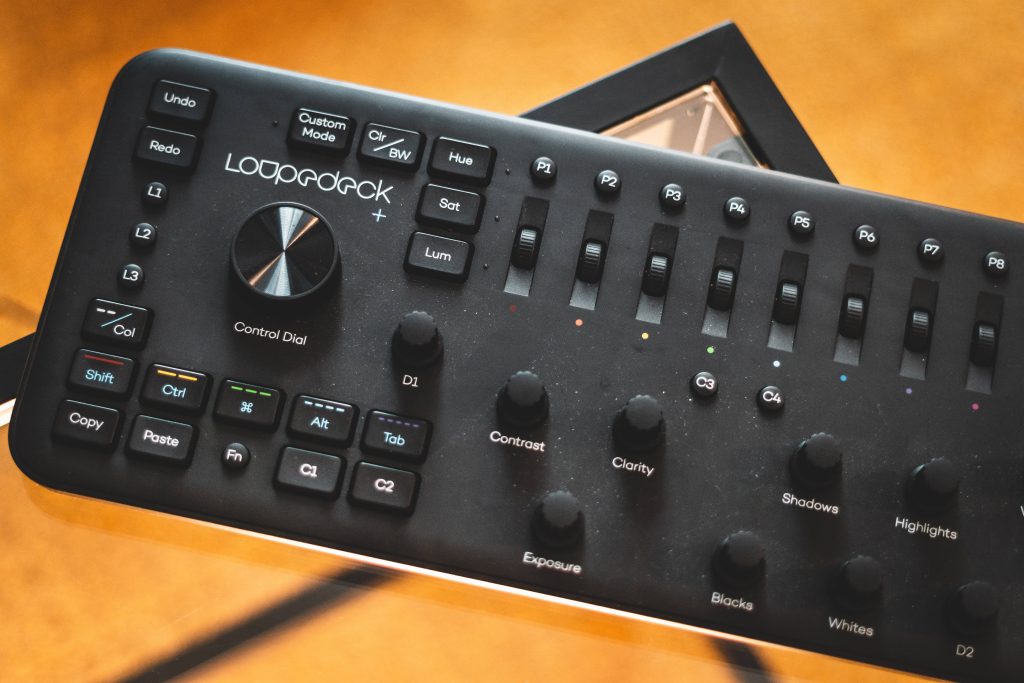 Loupedeck plus photo editing console with detailed dials and sliders on amber background wallpaper
