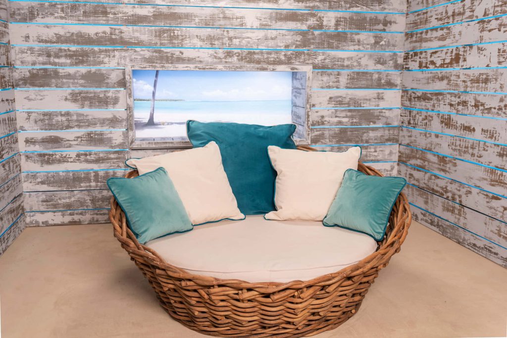 Love Island virtual background with cozy rattan chair teal cushions rustic whitewashed walls Wallpaper