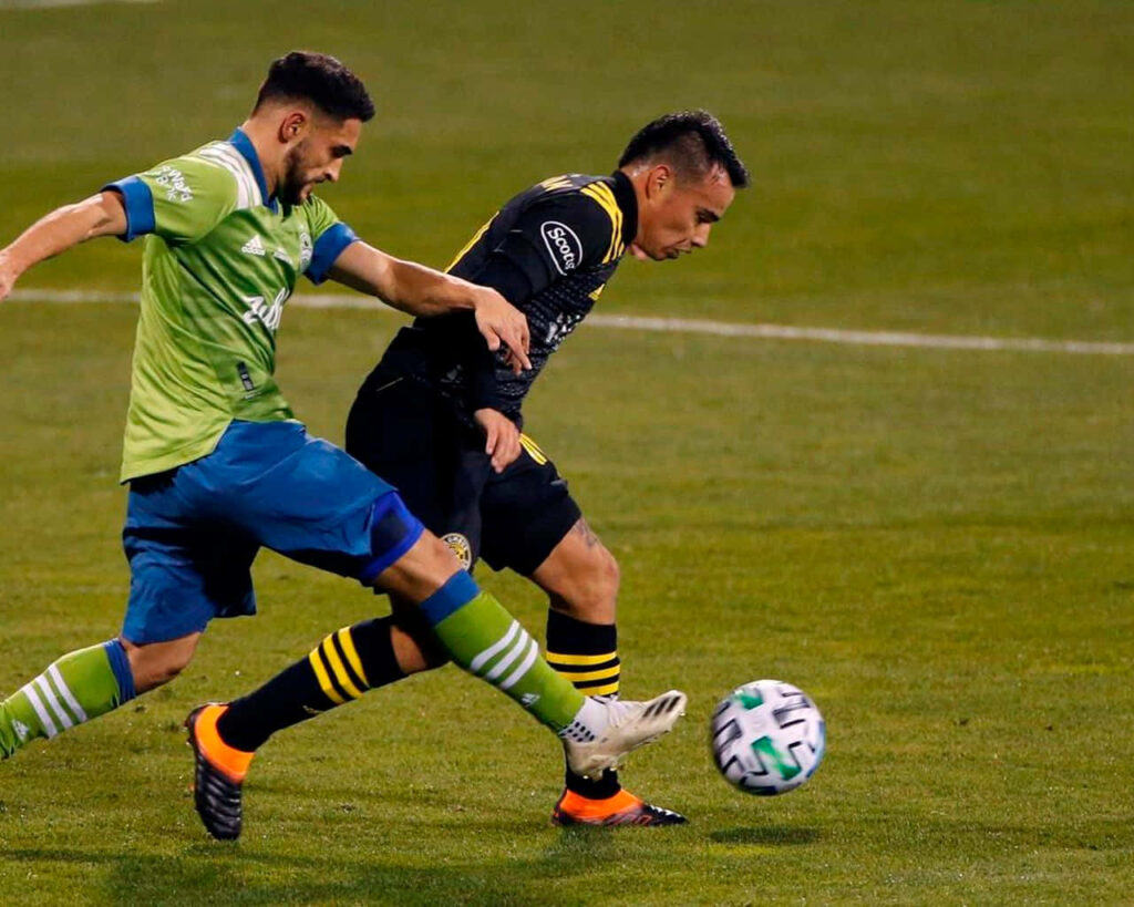 Lucas Zelarayan and Cristian Roldan competing intensely in vibrant Columbus Crew soccer match action Wallpaper
