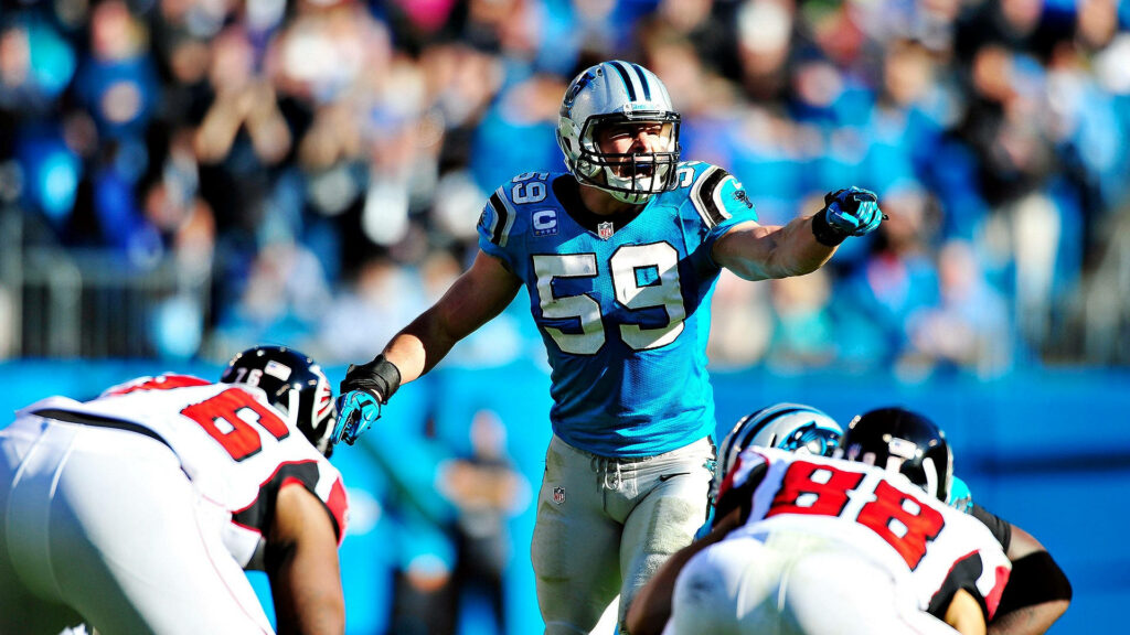Luke Kuechly Panthers linebacker in blue black uniform leads defense vibrant NFL stadium background Wallpaper