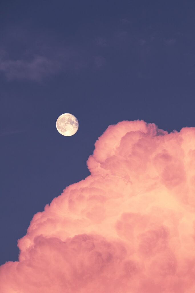 Luminous full moon above soft pink fluffy cloud in deep twilight sky serene wallpaper background