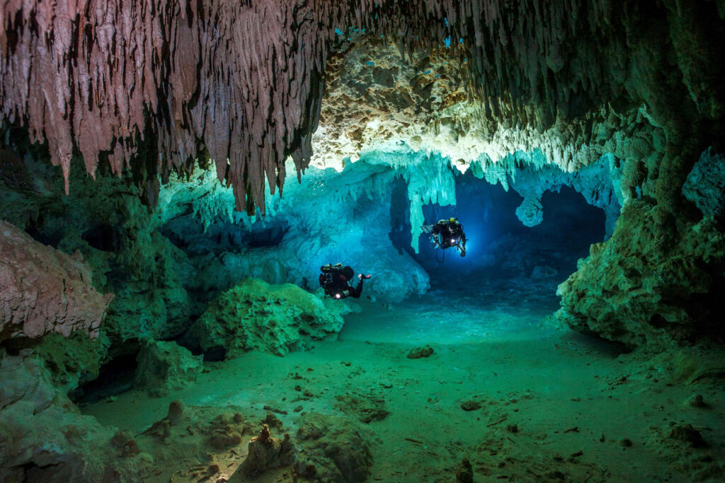 Mesmerizing Limestone Cave Wallpaper with Divers & Crystal Water