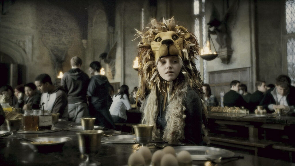 Loyal Luna Lovegood dons a Lion Head: Embracing Gryffindor in the Great Hall - Striking Harry Potter Background Image Wallpaper