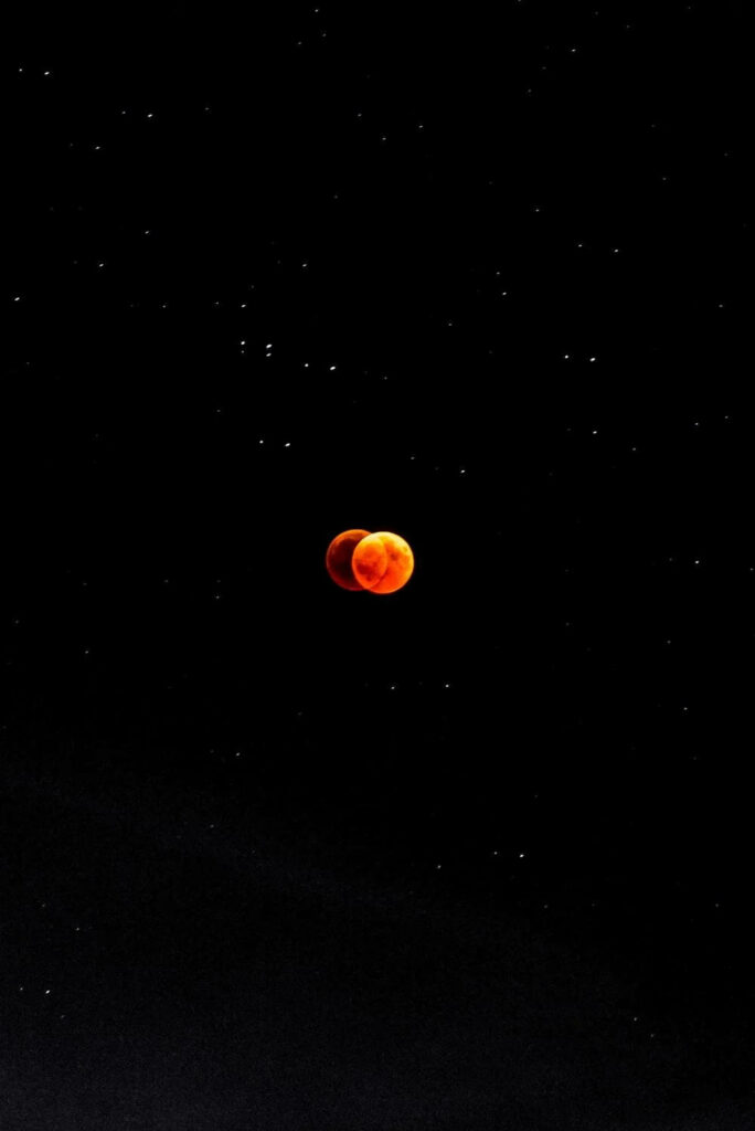 Stunning Lunar Eclipse Wallpaper: Reddish-Orange Moon & Starry Sky