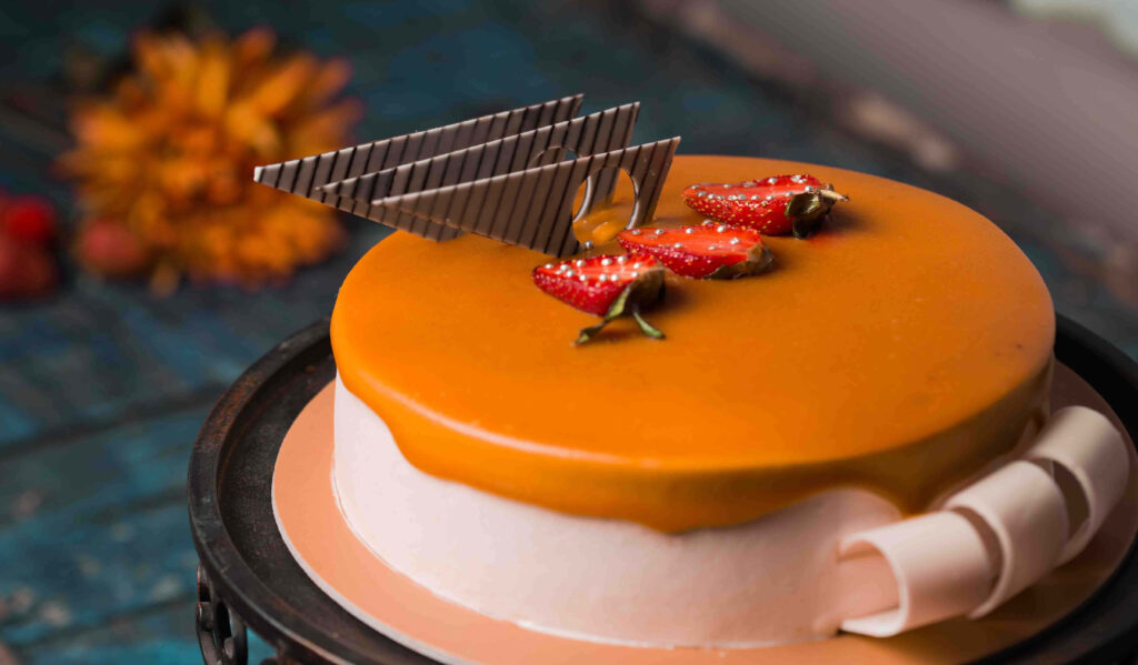 Caramel glazed cake with fresh strawberries and chocolate decorations on blue wallpaper background