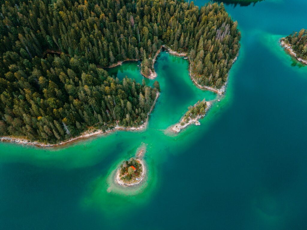 Aerial view of lush green island with dense forest surrounded by vibrant turquoise sea waters wallpaper