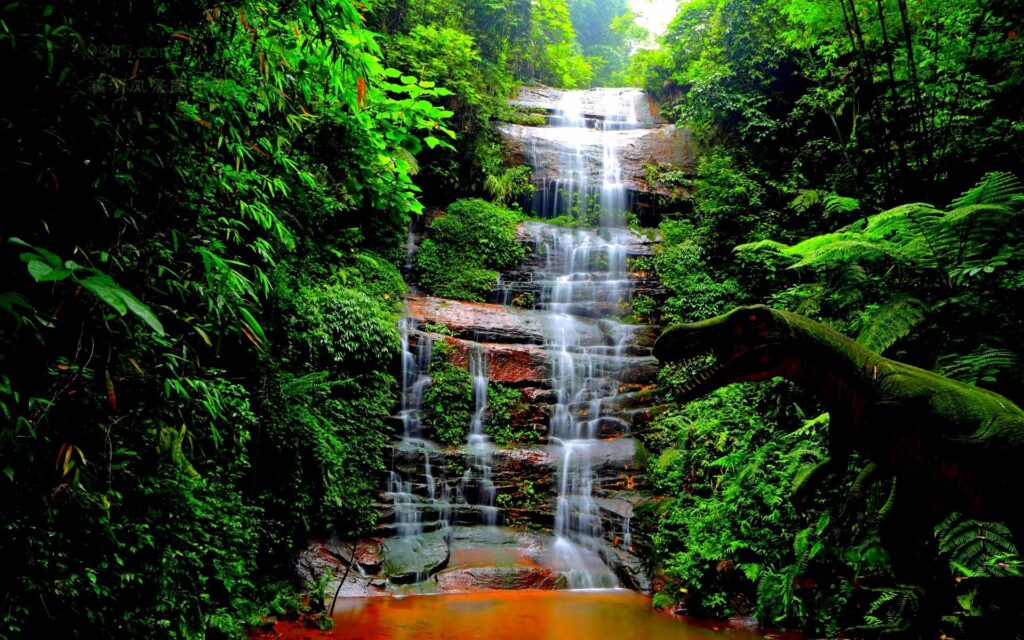 Lush jungle waterfall with vibrant trees and a fierce dinosaur creating a prehistoric scene Wallpaper