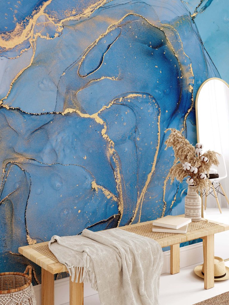 Cozy modern living space with blue marble wallpaper gold veining light rattan bench and decor