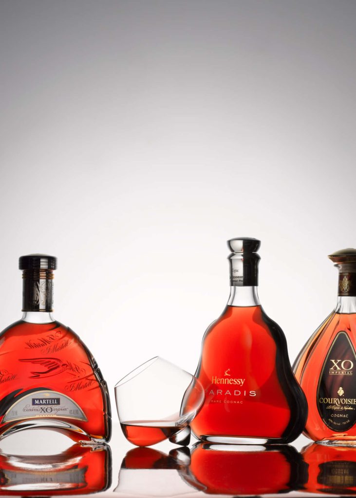 Premium cognac bottles Martell Cordon Bleu Hennessy Paradis Courvoisier XO with snifter glass studio photo Wallpaper