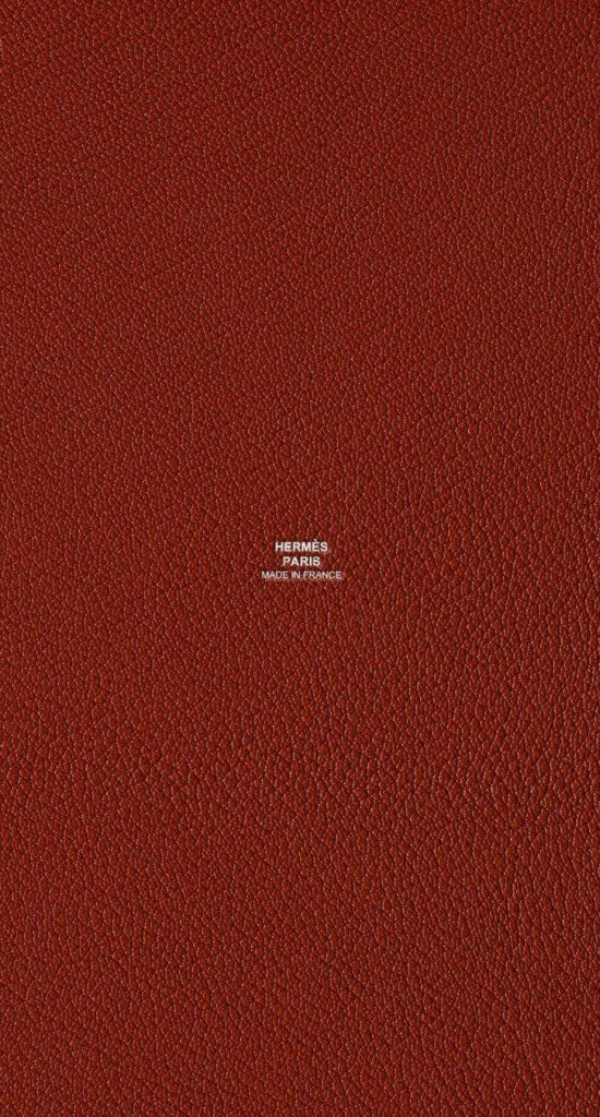 Copper textured Hermes leather wallpaper with embossed Hermes Paris logo luxury background