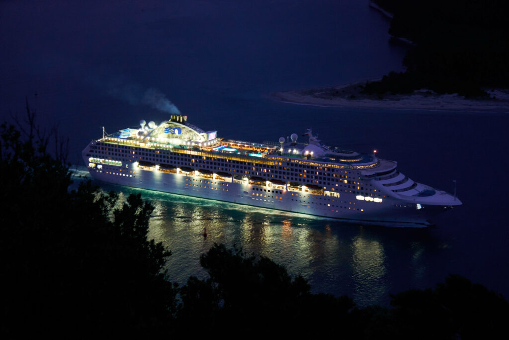 Luxurious cruise ship with glowing deck lights gliding across calm twilight waters wallpaper background