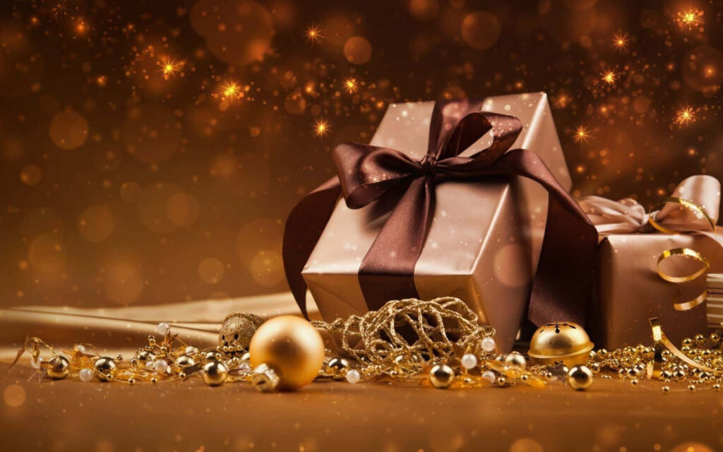 Festive gift box with dark brown ribbon surrounded by sparkling gold ornaments and decorations Wallpaper